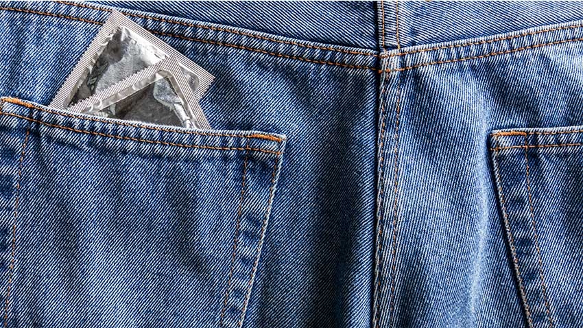 A photo of jeans back pocket with 2 condoms sticking out.