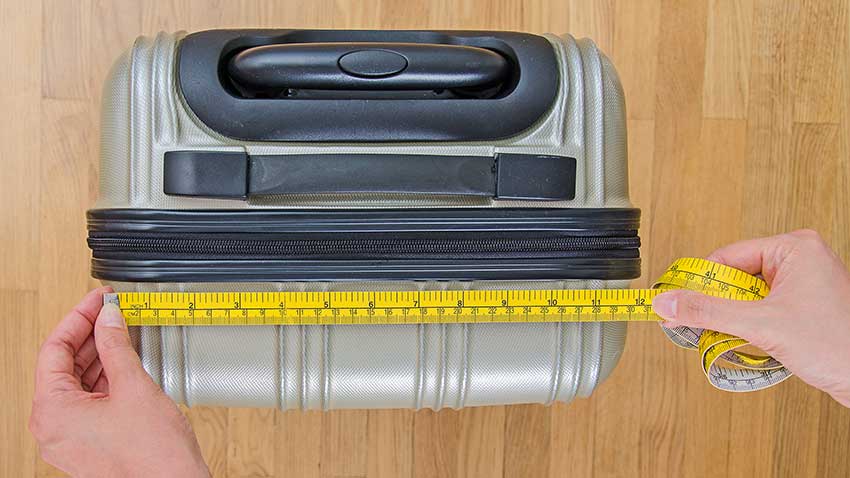 A suitcase being measured by a measuring tape.